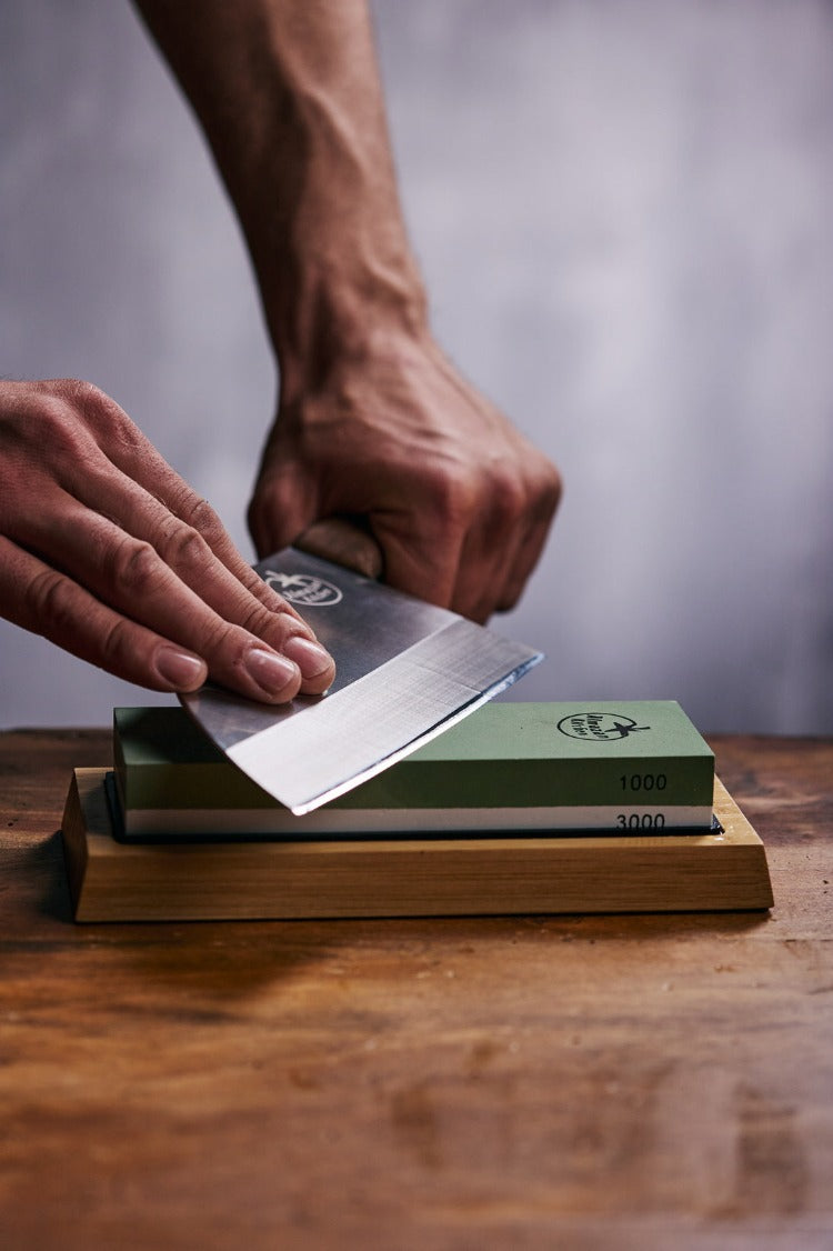 Person sharpening a chef knife on a Almazan Kitchen sharpening stone.