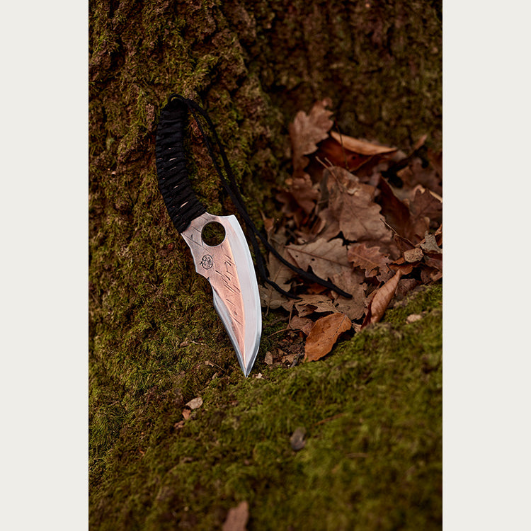 Almazan Kitchen Predator Knife leaning on a tree covered in moss.