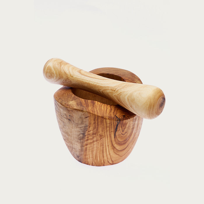 Wooden pestle set on top of a mortar with beautiful wood grains on a white background.