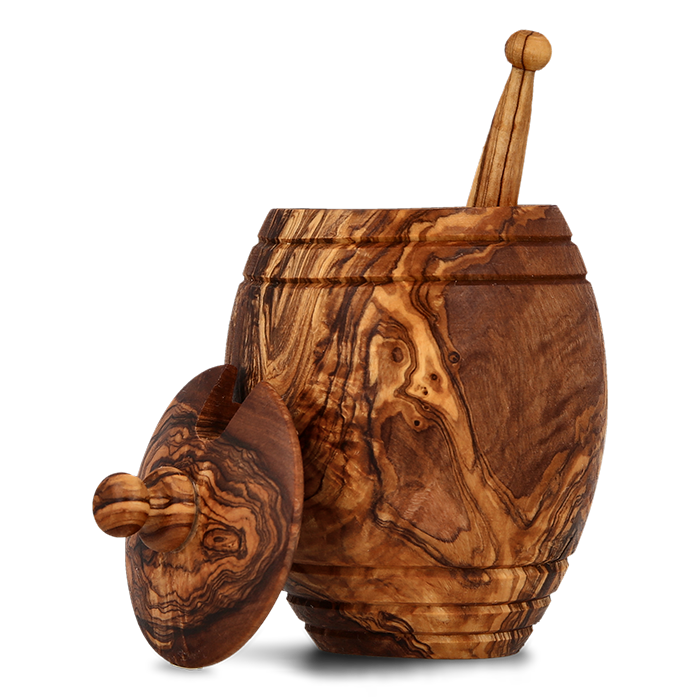 Ornate olive wood honey jar with dipper and lid on a transparent background.