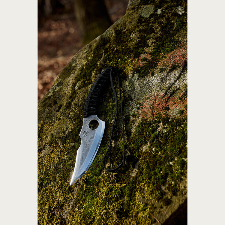 Almazan Kitchen Predator Knife on a stone covered in moss.