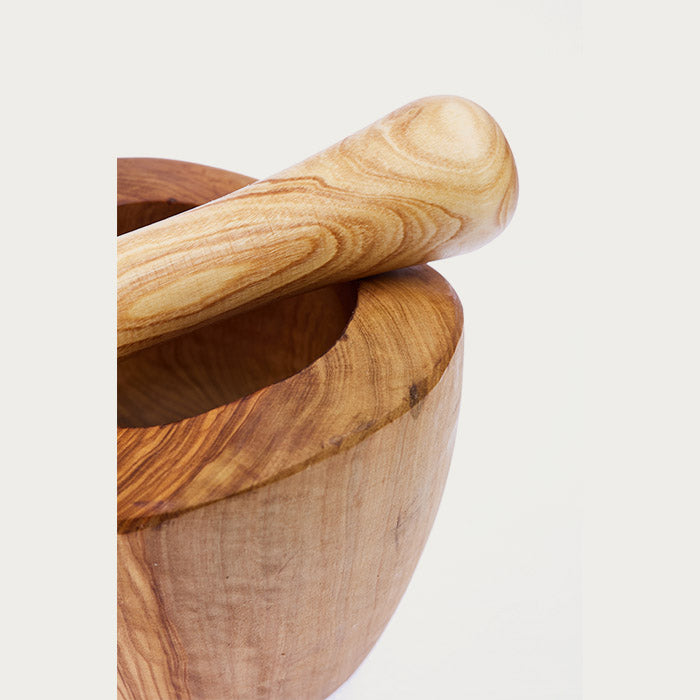 Close up of a wooden mortar and pestle with beautiful grains of wood displayed on a white background.