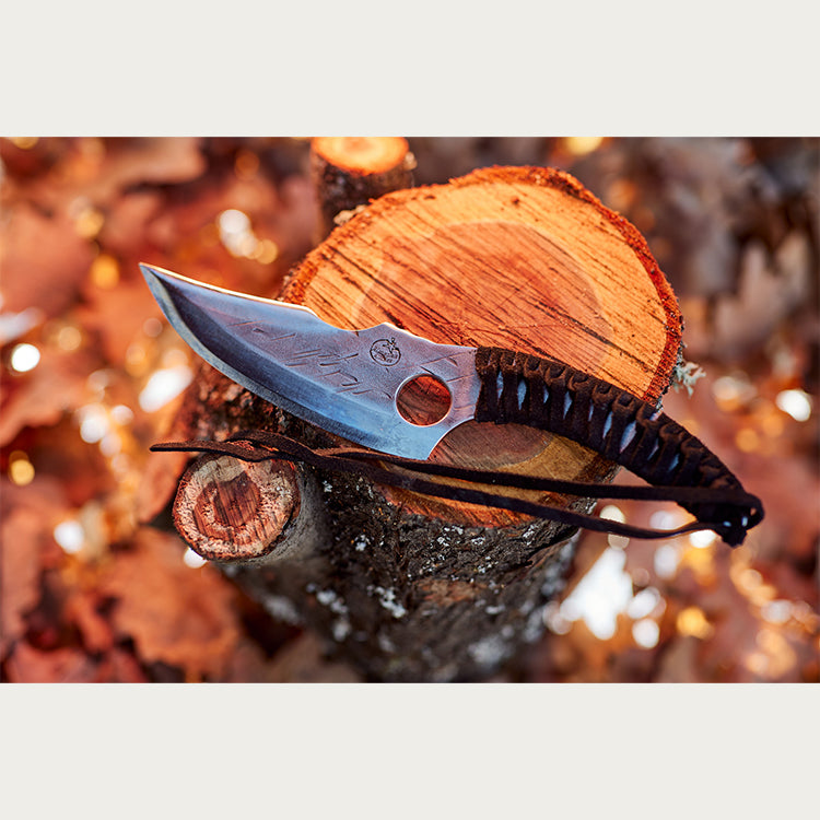 Almazan Kitchen Predator Knife on a tree trunk.
