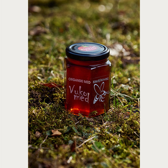 A jar of Almazan Kitchen organic honey on a mossy backdrop.