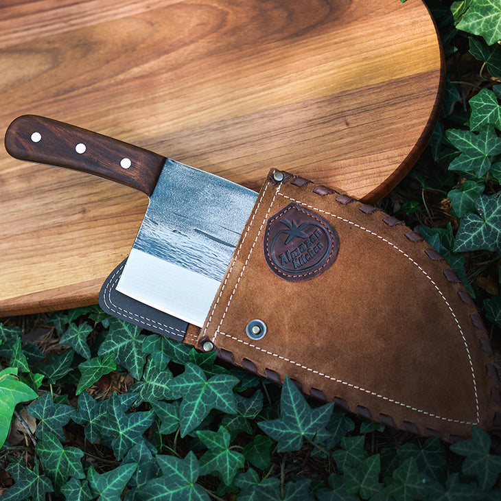 Serbian Chef Knife in a light brown leather sheath on a cutting board