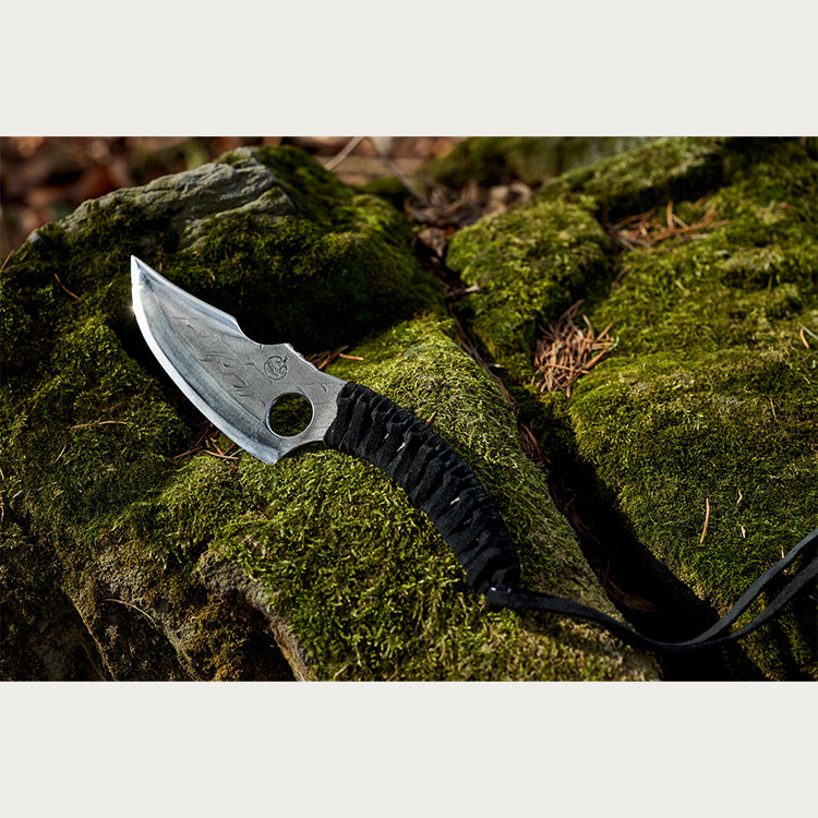 Almazan Kitchen Predator Knife on a stone covered in moss. 