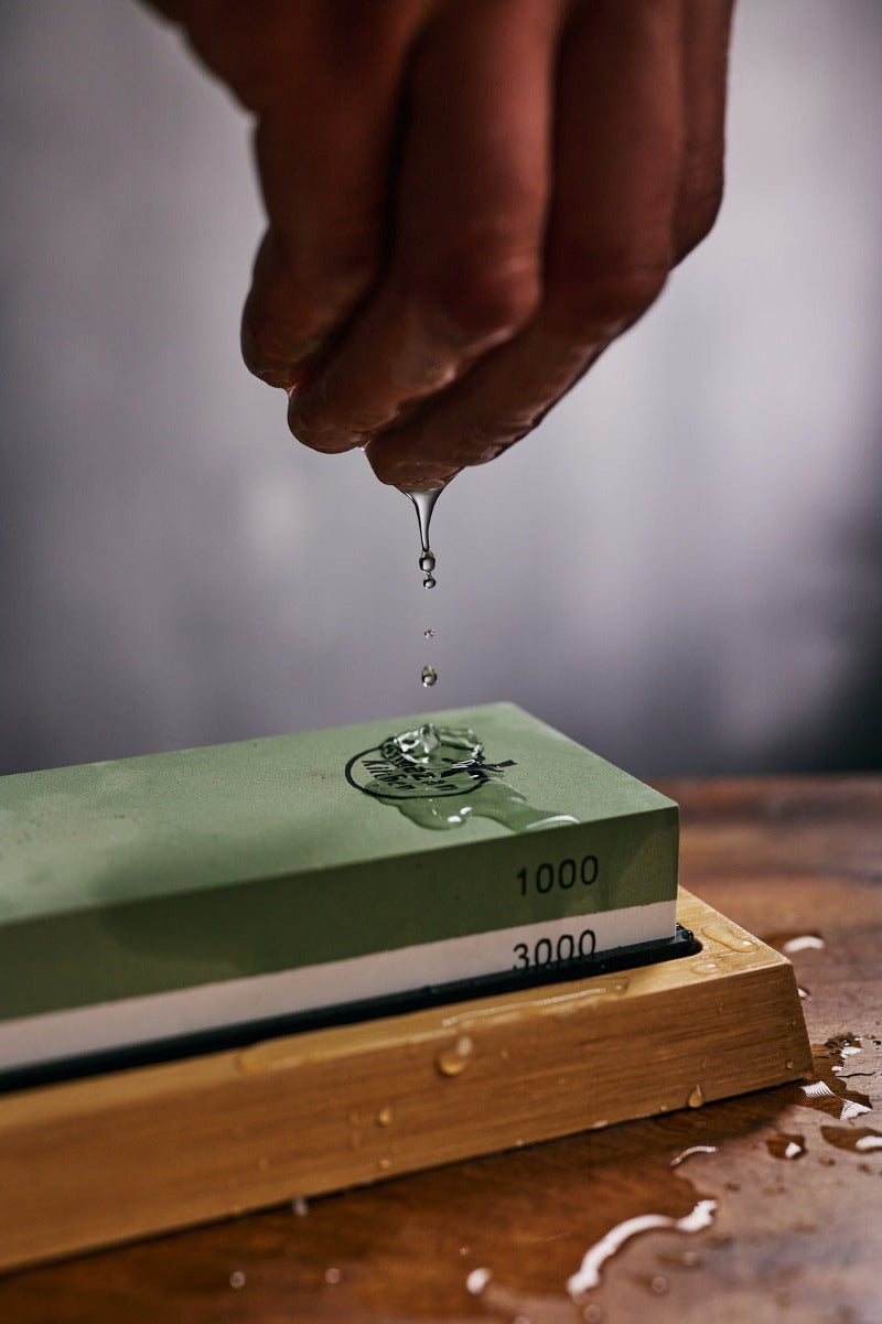 Water dripping from a hand on a Almazan Kitchen sharpening stone.