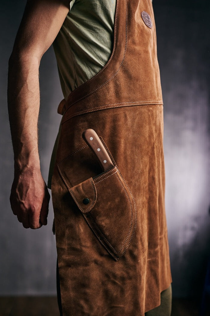 Man with a knife in the pocket of a Almazan Kitchen leather apron.
