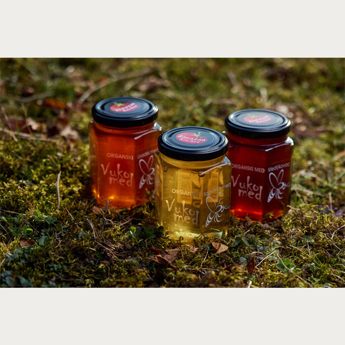 Three jars with different types of organic honey from Almazan Kitchen, on a mossy backdrop.