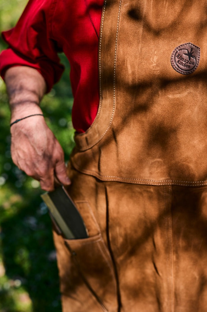 Man pulling out a chef knife from a pocket of an Almazan Kitchen apron.
