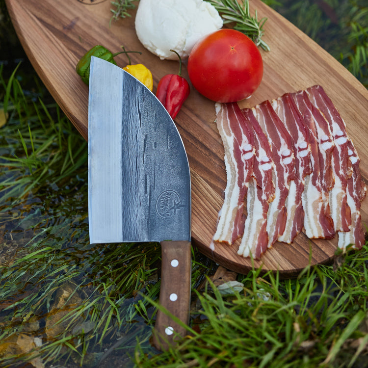 Almazan Kitchen cutting board with vegetables, meat and a Serbian Chef Knife on it.