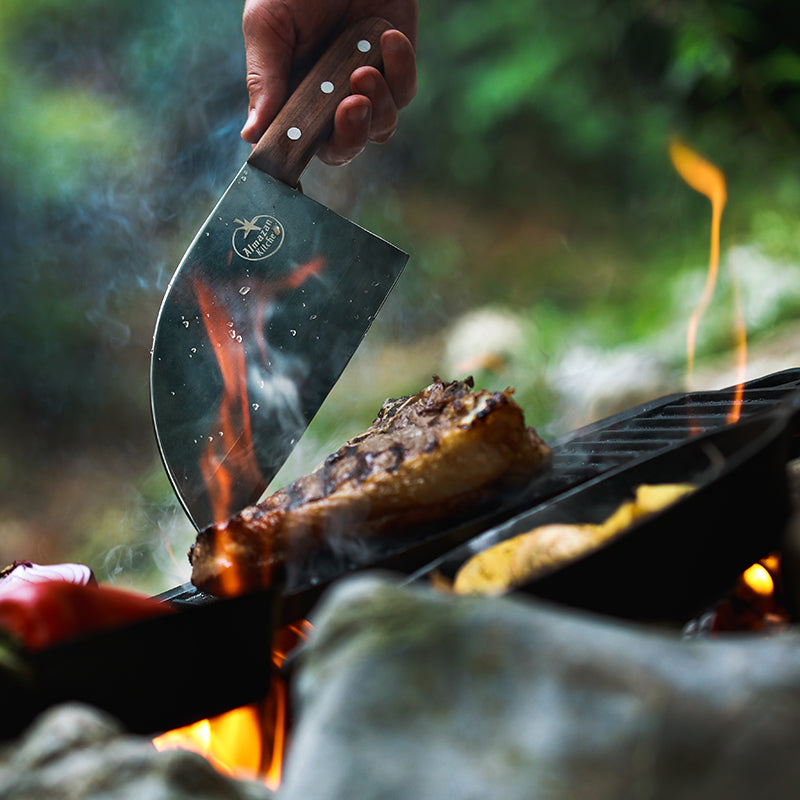 Promaja Knife cutting into a piece of steak cooking on a grill